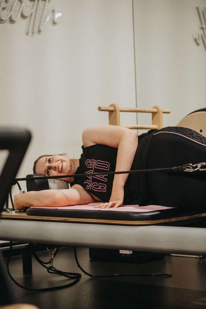 smiling woman doing refomer pilates