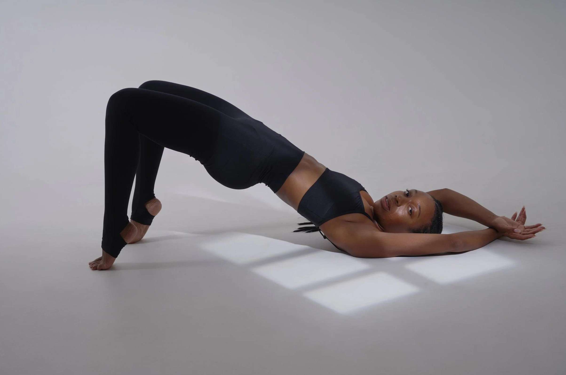 Woman performing a bridge exercise on a mat, engaging her core and pelvic floor muscles.